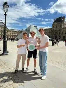 Studenten voor de piramide van het Louvre in Parijs, die de culturele aspecten van hun educatieve excursie belichten.