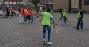 Levendige schoolpleinscène met diverse studenten die interactief deelnemen aan buitenspellen, bevorderend voor teamwerk en sociale ontwikkeling.