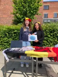 2 personen met decoratie in de kleuren van de belgische vlag, samen met het logo van Duik in taal